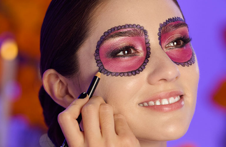 Mujer finalizando su maquillaje de Halloween de calavera con un lápiz